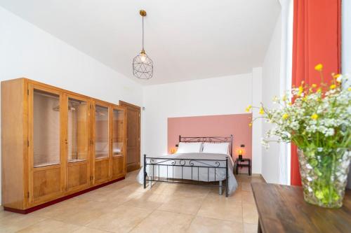 ein Schlafzimmer mit einem Bett und einem Tisch mit einer Blumenvase in der Unterkunft Casa Schiavoni in Forlì