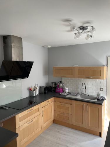 une cuisine avec des armoires en bois et un comptoir noir dans l'établissement La Maison de l'Auzette, à Limoges