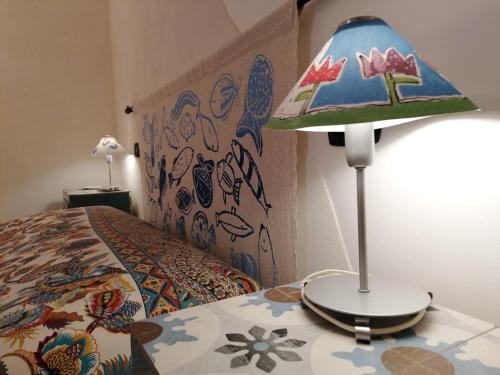a lamp sitting on a table next to a bed at Casetta BLU in Siracusa