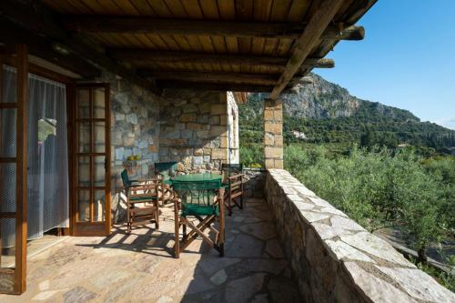 a patio with a table and chairs on a house at Porto Kalamitsi Stone-built Bungalows in Kardamili