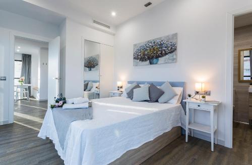 a white bedroom with a large bed and a table at New York Style Luxury 3 dormitorios in Jerez de la Frontera