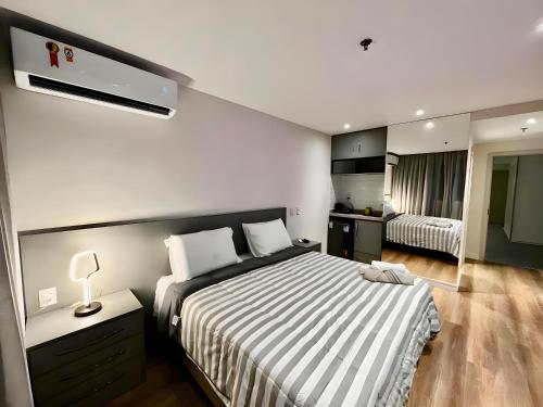 1 dormitorio con 1 cama grande y edredón a rayas en América apart-hotel, en Campos dos Goytacazes