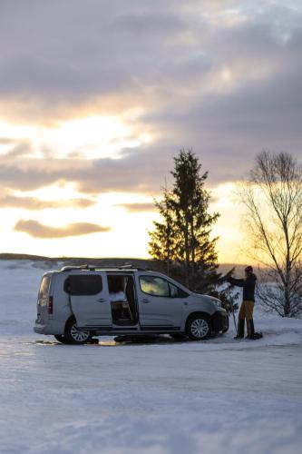 OsloCampervan في أوسلو: رجل واقف بجانب عربة في الثلج