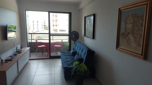 uma sala de estar com um sofá azul e uma mesa em Apartamento Intermares em Cabedelo