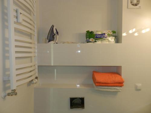 - une serviette orange assise sur une étagère dans une salle de bains dans l'établissement Apartament całoroczny Bliżej Morza, à Kołobrzeg