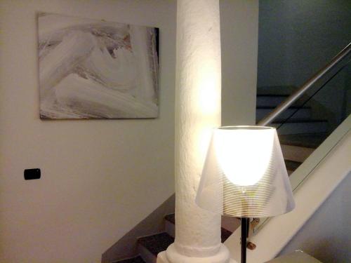 a white lamp next to a staircase with a painting at Hotel La Contrada in Verbania