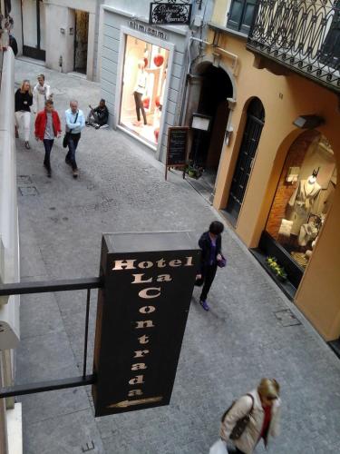a group of people walking down a street with a sign at Hotel La Contrada in Verbania
