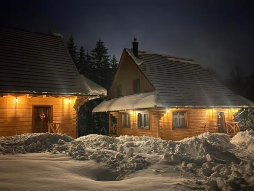 a house covered in snow at night with lights at Drevenice Kaskády Oščadnica Veľká Rača in Oščadnica