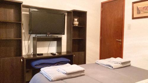 a room with a bed with a television and towels at Paz y armonía cerca de todo in San Salvador de Jujuy