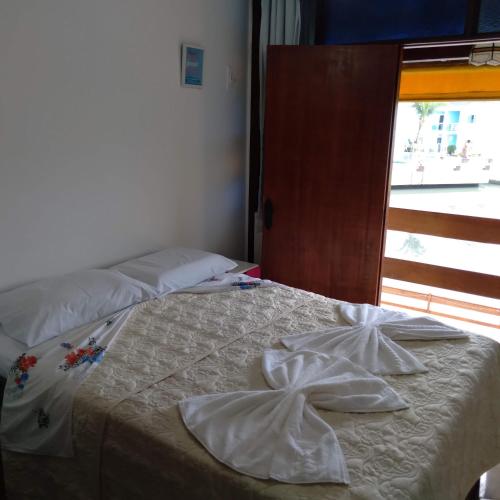 Una cama con dos toallas blancas encima. en Casa temporada., en Cabo Frío