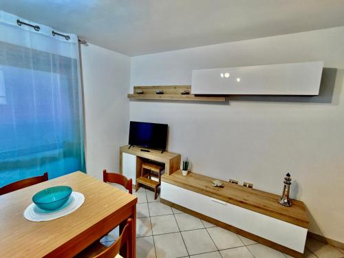 ein Wohnzimmer mit einem Tisch und einem TV in der Unterkunft "Da Roberto" in Stintino