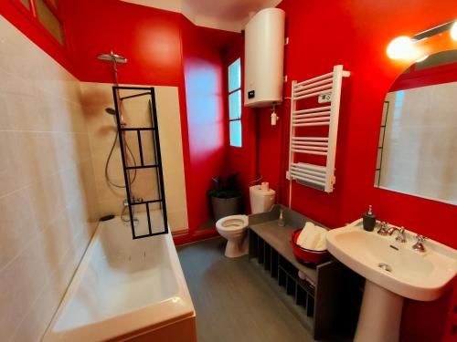 La salle de bains est pourvue de murs rouges, d'un lavabo et de toilettes. dans l'établissement Au petit châtillonnais, à Châtillon-sur-Seine