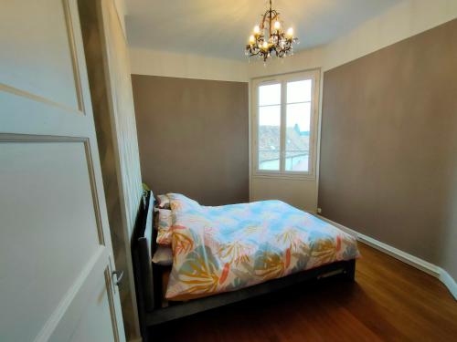 Un dormitorio con una cama con un edredón colorido y una ventana en Au petit châtillonnais, en Châtillon-sur-Seine