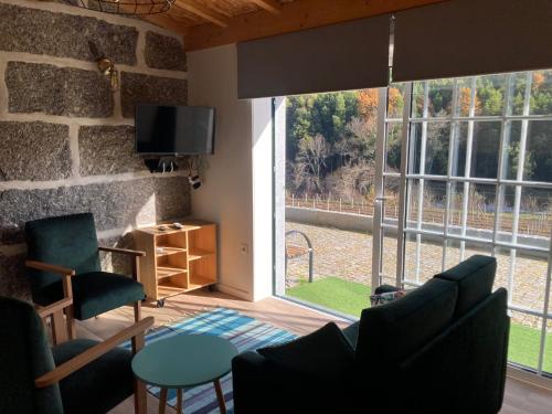 a living room with a large window and a tv at Quinta de Varzielas - Agroturismo in Castelo de Paiva
