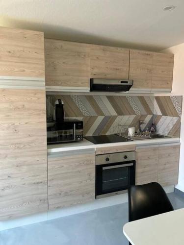 une cuisine avec des armoires en bois et un four à plaques de cuisson dans l'établissement Chez Jessica, à Chaumont-sur-Loire