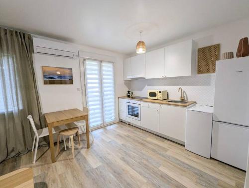 uma cozinha com armários brancos e uma mesa de madeira em Le numéro 1 em Perpignan