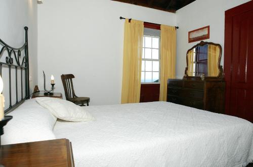 sypialnia z białym łóżkiem, komodą i oknem w obiekcie Casa Rural Tía ilia w mieście Puntallana