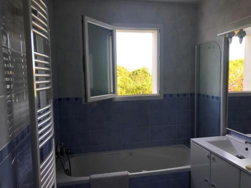 La salle de bains est pourvue d'une baignoire, d'un lavabo et d'une fenêtre. dans l'établissement La Villa W’ILLYS, à Montpellier