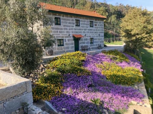 a stone building with purple flowers in front of it at Quinta de Varzielas - Agroturismo in Castelo de Paiva