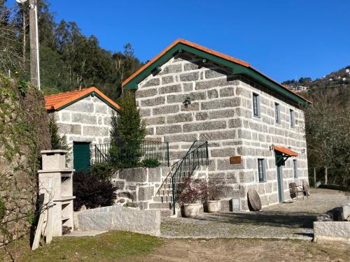 a stone building with a green door and a fence at Quinta de Varzielas - Agroturismo in Castelo de Paiva