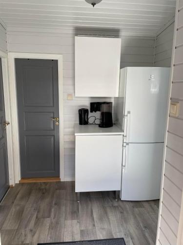 a kitchen with a white refrigerator and a door at Skottneset Feriesenter in Barmen