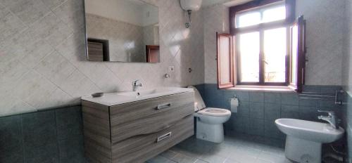 a bathroom with a sink and a toilet and a window at Pollino House in Morano Calabro