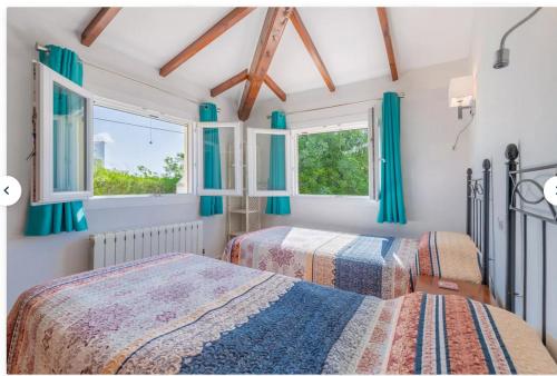 ベニタチェルにあるValle Verdeの青いカーテンと窓が備わるベッドルームのベッド2台