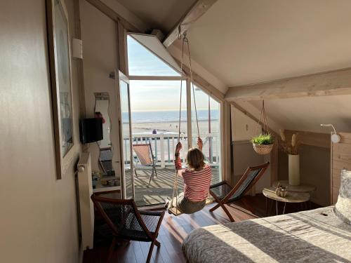 a little girl is jumping in a room with a balcony at Villa Trémail - La plage au pied de votre chambre in Wimereux