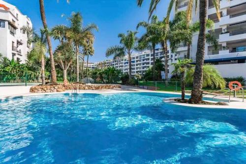 una gran piscina con palmeras y un edificio en PUERTO BANUS, 2 ROOMS, POOL AND PRIVATE PARKING., en Marbella