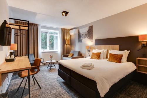 een hotelkamer met een groot bed en een bureau bij Hotel Ernst Sillem Hoeve in Den Dolder