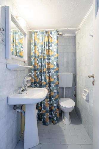 a bathroom with a sink and a toilet and a shower curtain at Renata Mare Beachside Studios in Hersonissos
