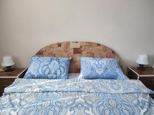 Cama con sábanas y almohadas azules y blancas en Apartman Kristina Ribarska banja en Kruševac