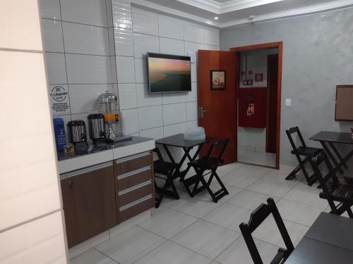 a kitchen with tables and chairs and a tv on the wall at Motel Softy (Adults Only) in Osasco