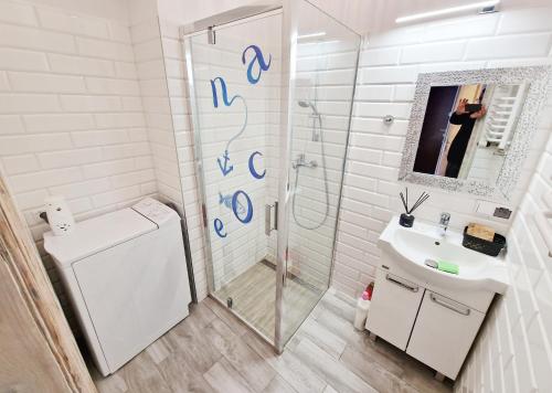 La salle de bains blanche est pourvue d'une douche et d'un lavabo. dans l'établissement Apartament Tuwim, à Przemyśl