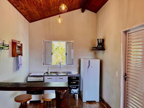 a kitchen with a white refrigerator and a counter at Chalé Verde morro da baleia. in Alto Paraíso de Goiás