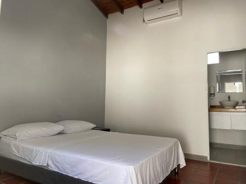 a bedroom with a white bed and a kitchen at LA VARIANTE in Zarzal