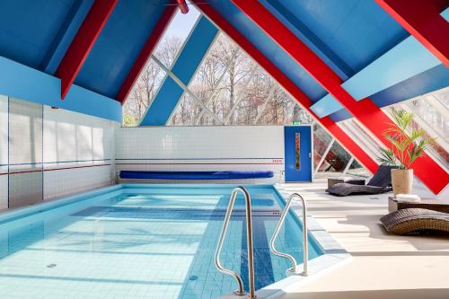 a swimming pool with a blue and red ceiling at Hotel Ernst Sillem Hoeve in Den Dolder