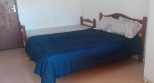 a bed with a blue blanket and pillows on it at Cantinho do Relax in Vera Cruz de Itaparica