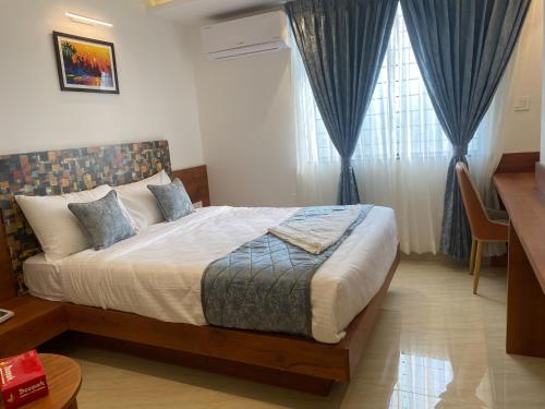 a bedroom with a large bed with blue curtains at The Urban Hive Hotel in Belgaum