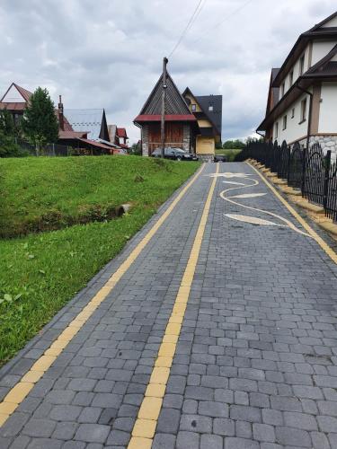 a cobblestone road with two yellow lines on it at LONDYNEK in Poronin