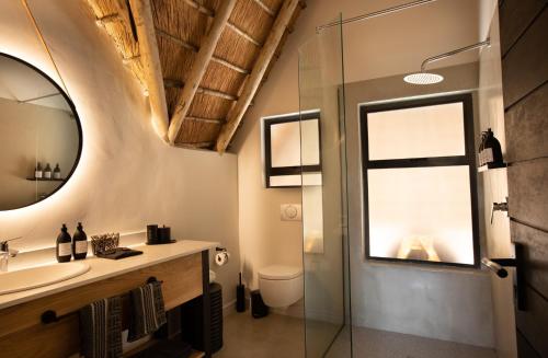 ソーニーブッシュ・ゲーム・リザーブにあるSerondella Game Lodgeのバスルーム(洗面台、ガラス張りのシャワー付)