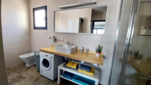 ein Badezimmer mit einem Waschbecken und einer Waschmaschine in der Unterkunft Casa Mykonos 1° linea de mar en Playa Blanca in Playa Blanca