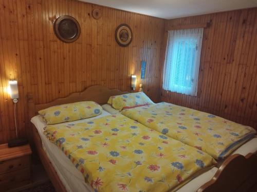 een slaapkamer met een groot bed en een gele deken bij Ferienhaus im Donauknie für Familien & Hunde in Leányfalu