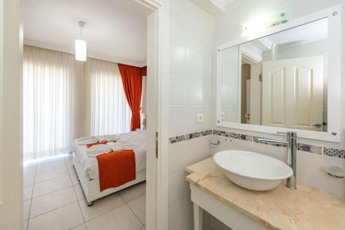 a white bathroom with a sink and a bed at Yaşam Park Rena Villaları Ölüdeniz in Fethiye