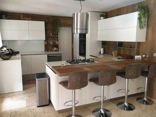 kuchnia z białymi szafkami oraz wyspa z barowymi stołkami w obiekcie Villa cosy 5km Cannes w mieście Pégomas