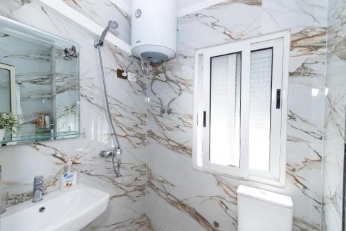 een badkamer met een wastafel en een raam bij ERLA'S apartment in Tirana