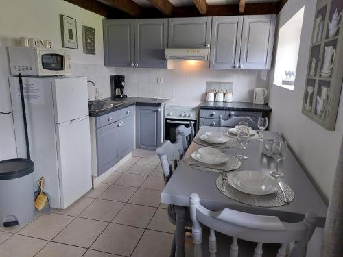 a kitchen with a table and chairs and a refrigerator at Les Gages in Brécé