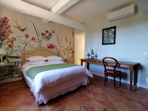 ein Schlafzimmer mit einem Bett, einem Tisch und einem Stuhl in der Unterkunft LA PERASCEDA in Spéracèdes