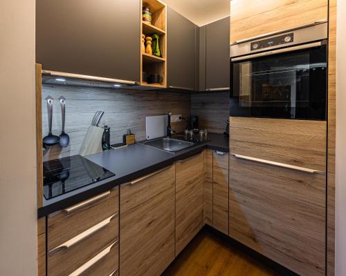 een keuken met houten kasten, een wastafel en een magnetron bij Horský apartmán Stella in Janov nad Nisou