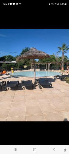 - une piscine avec un parasol et quelques bancs dans l'établissement Siblu village, à Valras-Plage